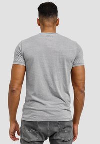 Grå kortærmet t-shirt i et blødt, glat stof. Har en rund halsudskæring og en ensfarvet ryg uden udsmykninger.
