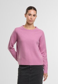 Rosa, gerippter Strickpullover mit langen Ärmeln und Rundhalsausschnitt; verfügt über eine leichte Textur und ein kleines Logodetail am Saum.