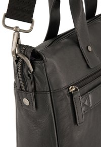 Schwarze Lederhandtasche mit Reißverschluss, verstellbarem Tragegurt, silberner Hardware und einer Fronttasche. Texturiert für Haltbarkeit und Stil.