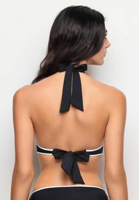 Svart bikini med halterneck-knytning och en rosett på ryggen. Vita accentlinjer på banden. Slät tyg med en mjuk textur.