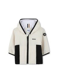 Veste zippée noire et blanche avec une surface texturée, une capuche et un patch de logo. Comprend des blocs de couleur contrastés et un intérieur doublé.