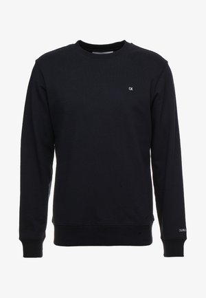 Schwarzer Sweatshirt mit Rundhalsausschnitt und langen Ärmeln, mit kleinem CK-Logo auf der Brust und Calvin Klein Schriftzug am linken Ärmelbündchen.