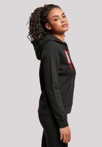 Black hooded sweatshirt with a kangaroo pocket, featuring red graphic text on the front. Cotton blend, medium weight, with ribbed cuffs and hem.