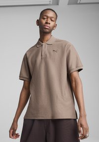 Brun polo t-shirt lavet af tekstureret stof, med korte ærmer og krave. Har et lille sort Puma-logo på brystet.