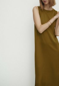 Robe sans manches vert olive avec une texture lisse et fluide. Design minimaliste avec un décolleté rond et une silhouette simple.
