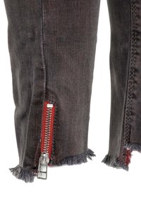 Jean en denim gris foncé avec un ourlet effiloché, présentant une fermeture éclair métallique avec un accent rouge sur le côté pour plus de détails.