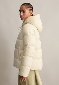 Daunenjacke in hellem Creme mit Kapuze, mit gestepptem Design, Kordelzugverschluss und seitlichen Taschen. Glatte, glänzende Textur.