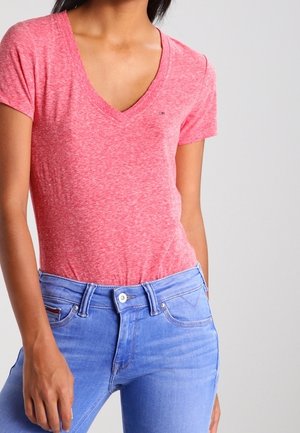 Rot meliertes V-Ausschnitt-T-Shirt mit kurzen Ärmeln, kombiniert mit hellblauen Jeans aus Denim mit Knopf- und Reißverschluss.