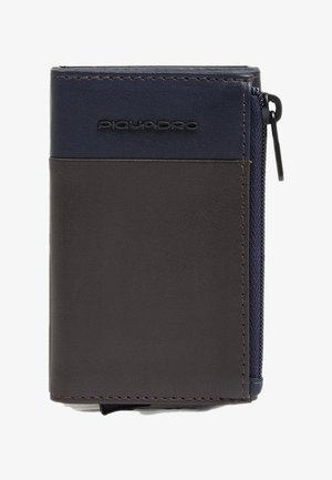 Cartera bicolor con cuero azul marino en la parte superior y cuero marrón oscuro en la parte inferior. Cuenta con cierre de cremallera y logo de la marca visible.