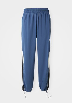 Pantaloni sportivi albaștri cu talie elastică, croială conică și panouri laterale negre. Include șnur la manșete și emblemă cu logo.