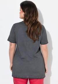 Grå kortærmet T-shirt lavet af blødt stof, med en afslappet pasform og rund halsudskæring. Forlænget ryg uden synlige mønstre eller detaljer.