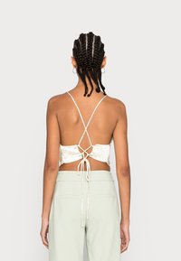 Top cropped floral com costas baixas, alças cruzadas ajustáveis e detalhe amarrado. Tecido leve com cores pastel delicadas.