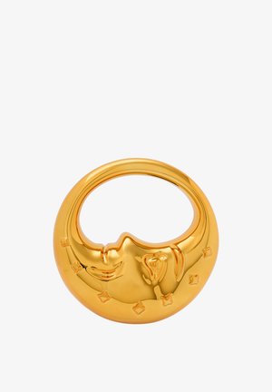 Kultasävyinen pyöreä esine, jossa on kasvojen kuvio, sileä pinta ja tähtielementtejä reunoilla. Heijastava pinta, moderni muotoilu.