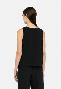 Black sleeveless top with a relaxed fit, featuring a round neckline and a small accent button at the back. Smooth texture and minimalist design.