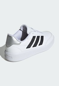 White sneaker with black stripes and silver accents. Features a smooth leather upper, rounded toe, and a textured rubber sole.