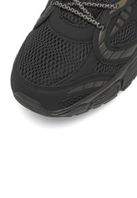 Čierne športové tenisky s kombináciou sieťoviny a syntetického materiálu, štruktúrovaným povrchom, kontrastnými akcentmi a vzorovanými šnúrkami.