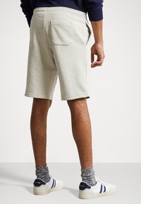 Světlé šedé tepláky s bočními kapsami a jednou zadní kapsou, které mají měkkou texturu látky a elastický pas pro pohodlí.