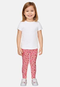 Maglietta bianca a maniche corte abbinata a leggings rosa con un motivo di orsi e fiori. Il modello indossa sneakers bianche.