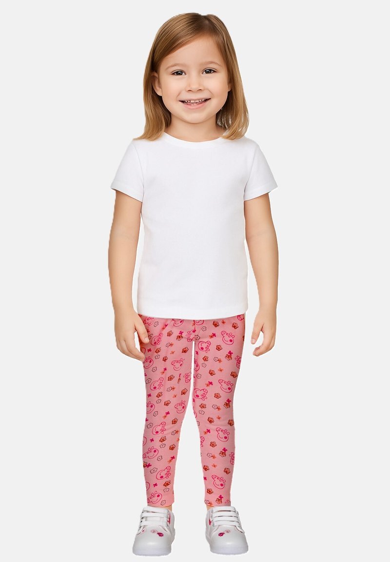 Maglietta bianca a maniche corte abbinata a leggings rosa con un motivo di orsi e fiori. Il modello indossa sneakers bianche.