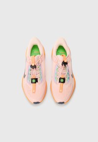 Baskets de sport rose clair avec une tige en maille, une doublure verte contrastante, des accents orange et un système de laçage à bascule noir.