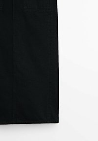 Jupe en denim noir à la coupe droite, dotée de deux poches et d'un ourlet net. Le matériau semble robuste avec une texture lisse.