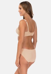Beżowy biustonosz i pasujące do niego majtki z wysokim stanem, wykonane z miękkiego materiału, z regulowanymi ramiączkami, falistymi krawędziami i bezszwowym wykończeniem.