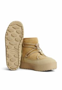 Brune ankelstøvler med en struktureret ruskindsoberdel, elastiske snørebånd og en tyk gummiplatformsål med et geometrisk mønster.