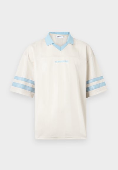 Polo à manches courtes blanc avec col bleu clair, deux rayures bleues sur chaque manche, et texte "J.LINDEBERG" en bleu clair sur le devant.