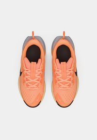 Pantofi sport portocalii cu un superior din plasă respirabilă, accente negre și o talpă texturată. Prezintă un logo proeminent și un design cu șireturi.