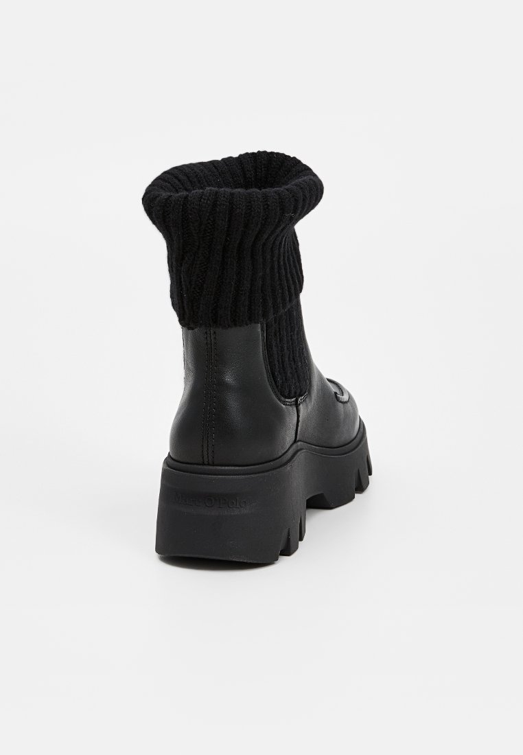 Schwarze Knöchelstiefel mit geripptem Strickbund, robustem Sohlenmaterial, glattem Lederoberteil und kontrastierenden Texturen. Verfügt über eine runde Zehenpartie und ein einfaches Anzieh-Design.