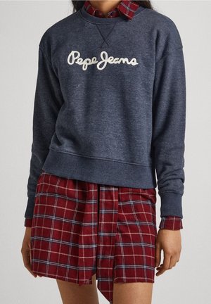 Navy sweatshirt met geborduurd "Pepe Jeans" logo, gecombineerd met een rood en geruit jurk met lagen. Materiaal lijkt zacht en textuur te hebben.