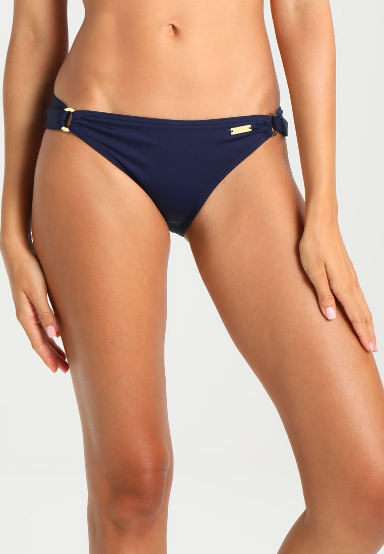 Marineblå bikini-bunn med en jevn tekstur, med sidesnorer og detaljer i gullfarge. Klippet i en lav midje-design.