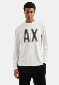 T-shirt bianca a maniche lunghe realizzata in morbido tessuto, con una grande grafica nera "AX" sulla parte anteriore. Stile slim fit, design semplice.