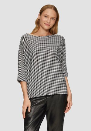 Zwart-wit gestreepte blouse met een bootnek, driekwartmouwen en een losse pasvorm, gecombineerd met zwarte leren broeken.