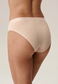 Beżowe bawełniane majtki o gładkiej fakturze, elastycznym pasku w talii i klasycznym kroju. Posiadają minimalne szwy i bezszwowe krawędzie dla wygody.