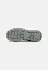 Gray shoe sole featuring a textured pattern with rectangular grooves and a rounded toe, designed for traction and stability.