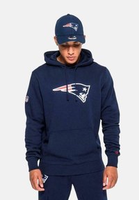 Set di felpa e cappellino blu navy con il logo dei New England Patriots; texture morbida, con lacci sulla felpa e visiera curvata sul cappellino.