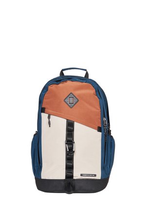 Mochila con paneles en azul, beige y crema. Cuenta con una correa negra, bolsillos frontales con cremallera y una base duradera. El material parece resistente y texturizado.