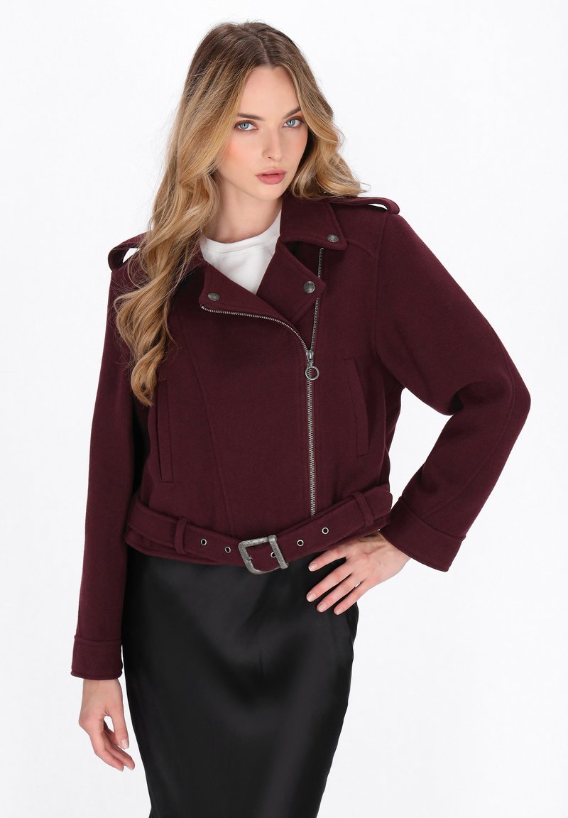 Burgundi vörös cropped dzseki, cipzáros elülső résszel, patent gombokkal, vállpántokkal és övvel a derekán; gyapjú keverék anyagból készült.
