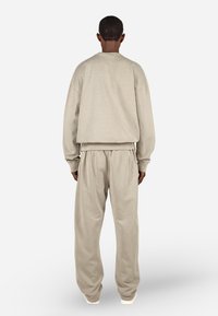 Béžová oversized mikina a zodpovedajúce tepláky s rebrovanými manžetami a pásom. Mäkkučká, textúrovaná látka s voľným strihom.