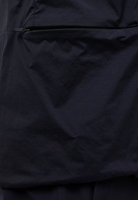 Marineblaues Windbreaker mit strukturiertem Finish und einer mit Reißverschluss versehenen Tasche auf der Vorderseite. Leichter, strapazierfähiger Stoff mit matter Optik.