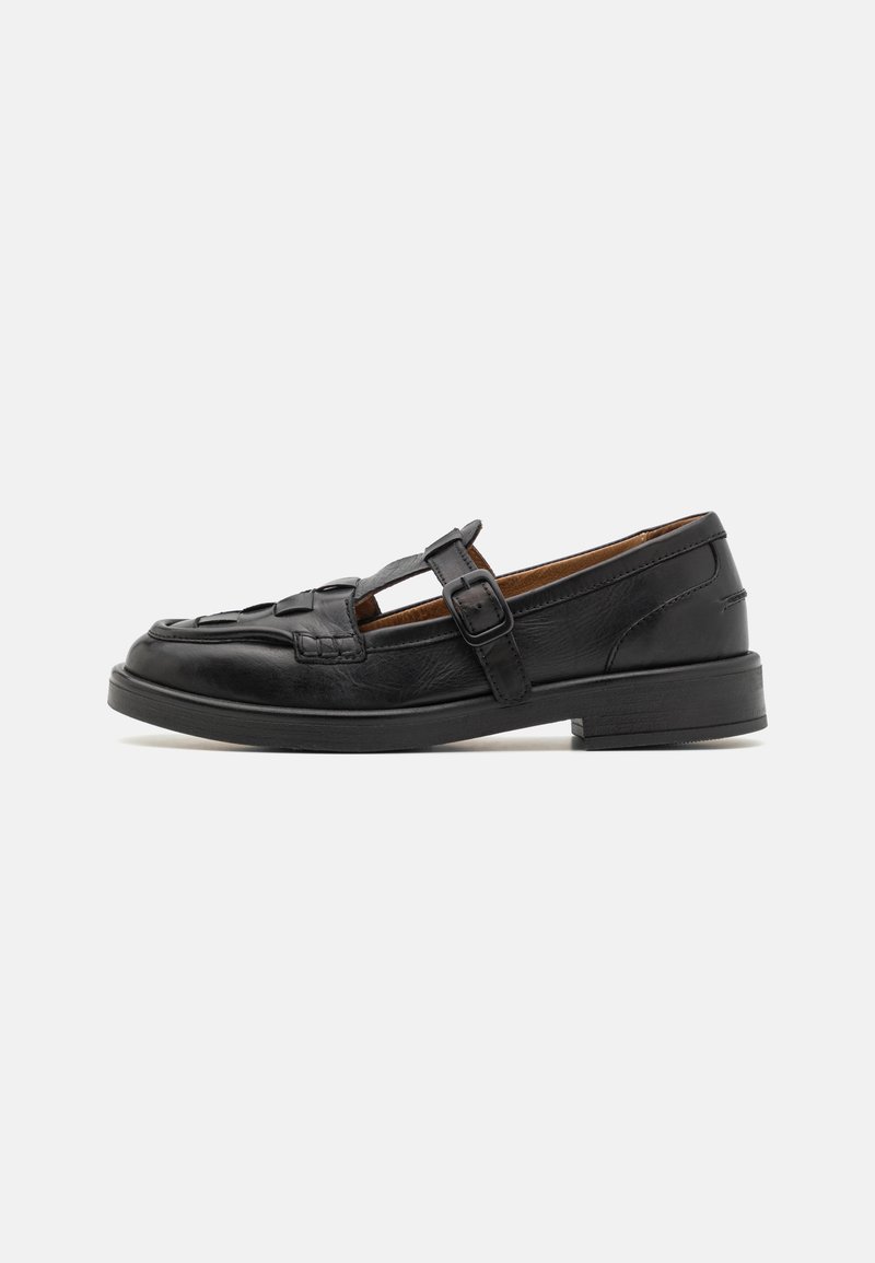 Black leather shoe with a woven pattern, T-bar design, and a side buckle. Features a low, rounded heel and smooth texture.