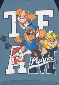 Felpa blu con cani animati, con grandi lettere bianche "TEAM" e "Players" in corsivo, dettagli colorati e accenti a forma di impronta di zampa.