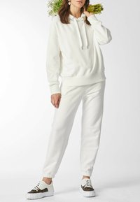 Witte hoodie met trekkoorden, bijpassende joggerbroek en sneakers met patroon. Zachte stof, ontspannen pasvorm, geribbelde manchetten en zoom.