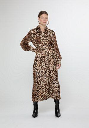 Vestido camisolado con estampado de leopardo en tejido de satén, que presenta mangas largas, cintura ceñida con cinturón y diseño de longitud media. Se lleva con botas negras hasta la rodilla.