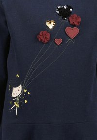 Marineblaues Sweatshirt mit floralen und herzförmigen Applikationen in Rot, pailettenbesetztem Schwarz und goldenen Akzenten. Mit einem verspielten Druck eines Kindes mit Luftballons.