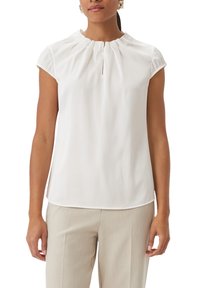Blouse blanche à manches courtes avec un col froncé et des plis subtils. Tissu léger, texture douce et coupe décontractée.