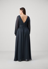 Robe longue, bleu foncé, en chiffon lisse avec des manches longues et une taille cintrée. Présente un dos en V profond et des détails plissés au niveau du corsage.