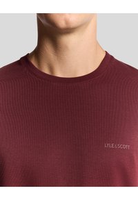 Bordo krāsas apaļas apkakles T-krekls no mīksta kokvilnas. Uz krūtīm smalka izšuvuma logotips. Gluda tekstūra un pieguļošs dizains.