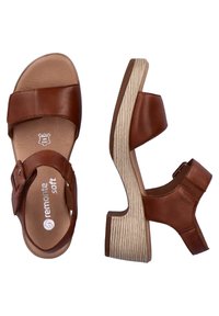 Brown leather sandals with two wide straps, featuring a block heel and textured wooden sole. Adjustable ankle strap for fit.